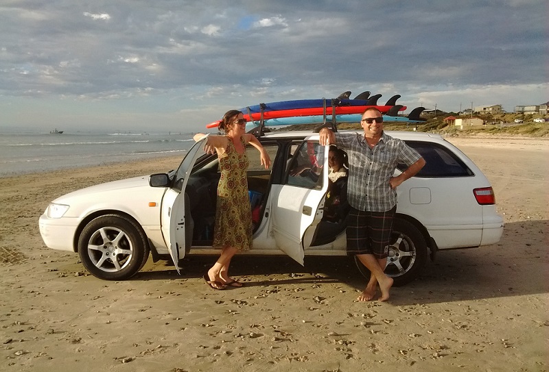 Ruth and Jared next to surfboard-equipped car on Aldinga Beach, South Australia. 
