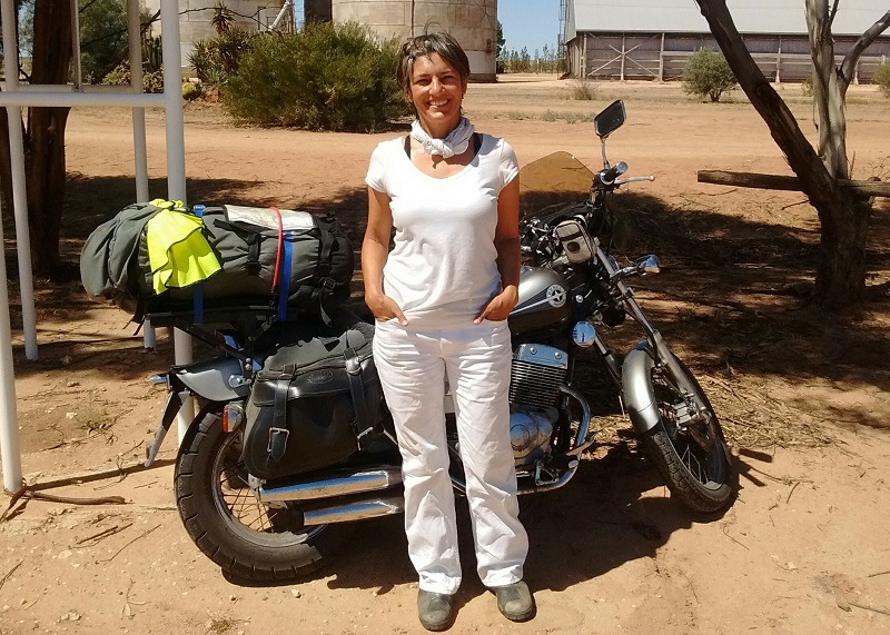 Ulrike dressed all in white in front of the gear-loaded Honda Rebel in Australia.